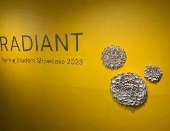 Radiant showcase title sign with Gia Wahle's Purchase Award winning porcelain piece "Perpetual Spring" featured on sign