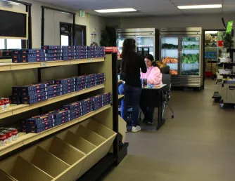 student checking out with another student in a grocery store setting