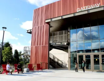 The Gateway building is pictured with students sitting in red chairs in front of it.