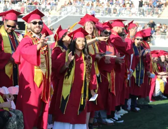 A group of military veteran graduates stand during the commencement ceremony to be recognized for their military service.