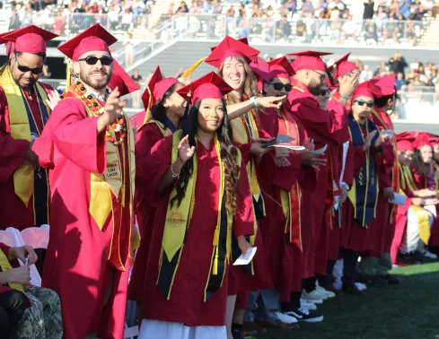 A group of military veteran graduates stand during the commencement ceremony to be recognized for their military service.