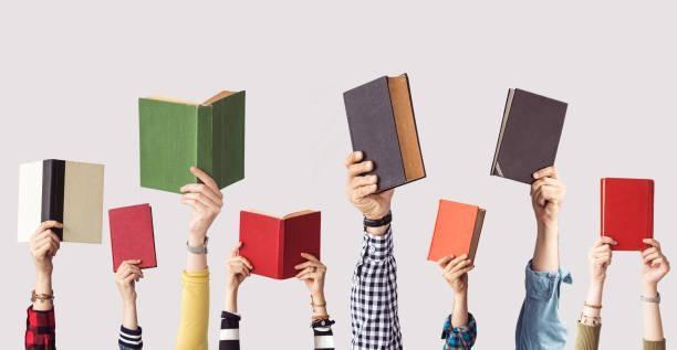 A group of hands holding up books.