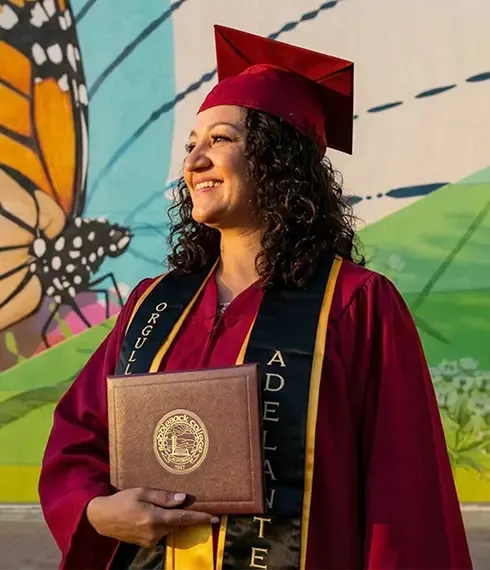 Woman in regalia holding a diploma.